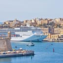 A panoramic view of Valletta's Grand Harbor in Malta, with a large cruise liner anchored in the bay.
