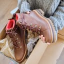 A woman taking out brand new brown leather boots from a shoebox 
