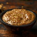 Close-up shot of a bowl of whole grain mustard served on a rustic wooden table.