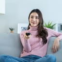 close-up of a young woman enjoying a comedy on TV while relaxing on a sofa at home