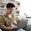 Smiling man using his laptop on the sofa indoors