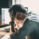 Tired and worried business man at workplace in office holding his head on hands after late night work, concept