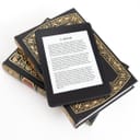 E-reader placed on top of two paper books against white background