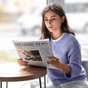 A young woman reading a newspaper in a cafe