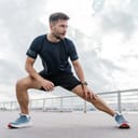 close-up of a young man doing warm-up exercises on a dock, wearing sporty clothes and a smartwatch