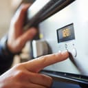 close-up of a man's hand pressing a button to start a microwave timer for cooking