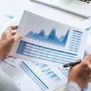 Person with a pen in one hand looking at data charts