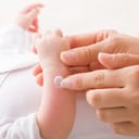 A closeup of a woman applying cream on a baby's arm