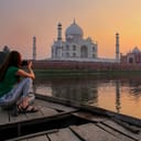 young woman on a boat admiring and taking a photo of the sunset over the Taj Mahal in Agra, India