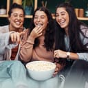 Christmas isnt complete without a fun movie marathon. Shot of young sisters having popcorn and watching tv together during Christmas at home.