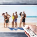 A person holding a remote control watching a reality show