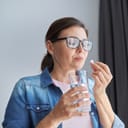 portrait of a mature woman taking a pill with a glass of water at home