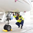 A man crouching under an airplane nose making final checks