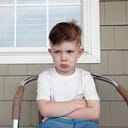 Small boy sulking on a chair