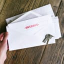 Woman holding an envelope reading 'overdue' with keys on the table