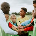 A junior football team stacked their hands on top of each other together with their coach before a match.