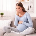 Nauseated pregnant woman sitting on couch