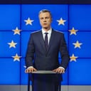 A politician standing in front of a flag of European Union displayed on screens behind him
