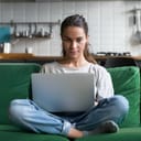 Woman sitting on a couch with legs crossed an a laptop in her lap