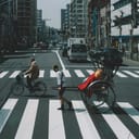 man in a white t-shirt and black shorts pulling a Japanese rickshaw at a pedestrian crossing