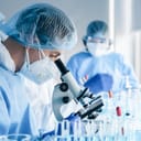 a biochemical research scientist team working in a lab with a microscope and wearing safety equipment