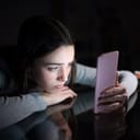 A closeup of a depressed young girl looking at her phone