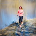 Fitness girl jogging in park near pond in the frosty morning. Running woman training near the lake in cold weather