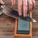 Man sharpening a kitchen knife against a whetstone