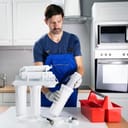 a man installing a water purification filter in the kitchen