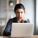 A serious young woman looking at a laptop