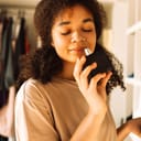 close-up of a teenage girl enjoying the scent of perfume from a glass bottle with her eyes closed