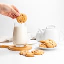 Chocolate chip cookie being dipped in milk.