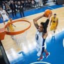 excited basketball player scoring a two-handed slam dunk during the match