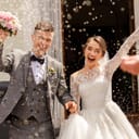 Photo of bride and groom smiling at their wedding ceremony while being sprinkled with rice