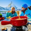 family enjoying Swiss fondue with Matterhorn mountain view in Switzerland