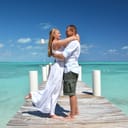 Embraced wedding couple standing on a pier at oceanside