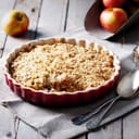 Apple crumble on the wooden background with apples .