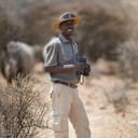 A ranger holding binoculars in the African savana