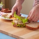 Person preparing a sandwich on table