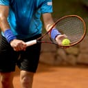 A closeup of a tennis player getting ready to serve