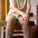 Elderly person holding their knee with both of their hands