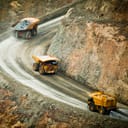Three massive trucks transporting rubble in a quarry