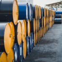 stack of used 55-gallon oil drums in a storage yard