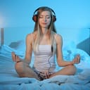 Woman meditating in her bed while wearing headphones