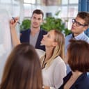 Group of young people gathered around a whiteboard at an office