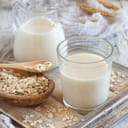 Milk in a glass and creamer along with spoons with oats in them