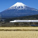 Shinkansen bullet train on the Tokaido Shinkansen line with Mount Fuji and rice fields.