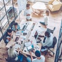 Above view of an office full of employees working around one desk