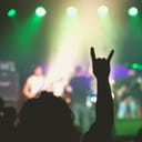 A person holding Devil's Horns, a rock and roll symbol, at a concert