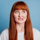 portrait of a red-head girl biting her lip, appearing guilty, isolated on a blue background